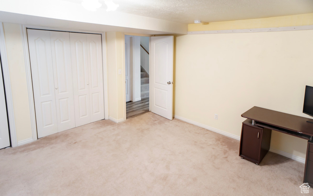 Unfurnished office with light colored carpet, baseboards, and a textured ceiling