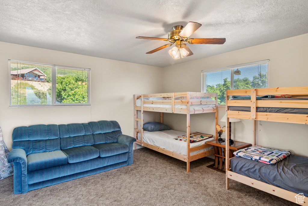 Bedroom with carpet floors, a textured ceiling, and ceiling fan