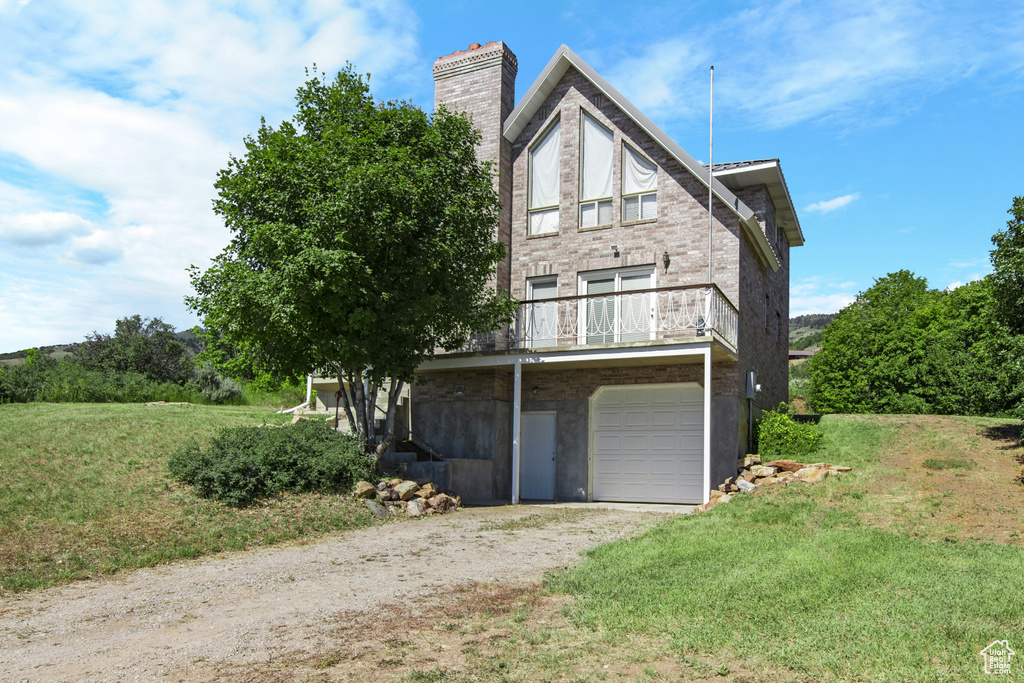View of front facade with a chimney, dirt driveway, and an attached garage