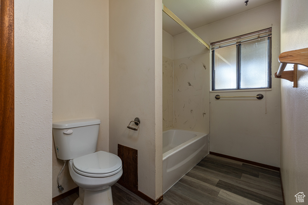 Bathroom with wood finished floors, toilet, and shower / bath combination
