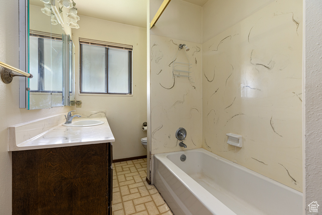 Bathroom featuring brick patterned floors, toilet, vanity, and tub / shower combination