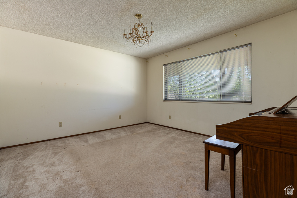 Unfurnished bedroom featuring light carpet, a chandelier, baseboards, and a textured ceiling
