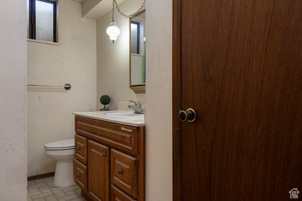 Half bathroom with brick patterned flooring, toilet, and vanity