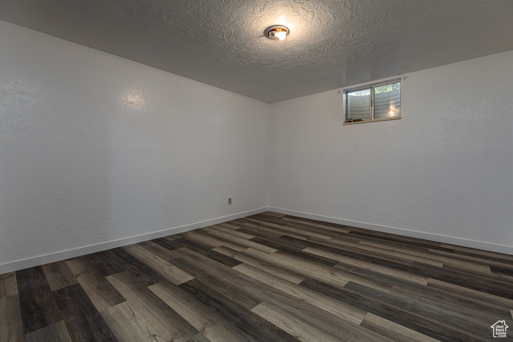 Unfurnished room with dark wood-type flooring, baseboards, and a textured ceiling
