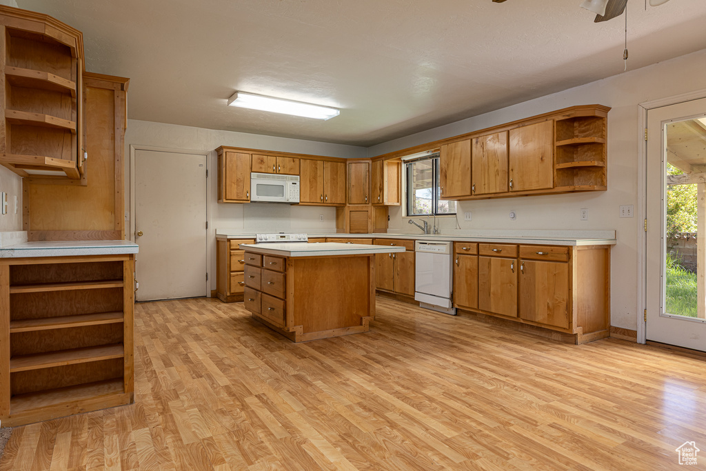 Kitchen with open shelves, white appliances, light wood-type flooring, brown cabinets, and light countertops