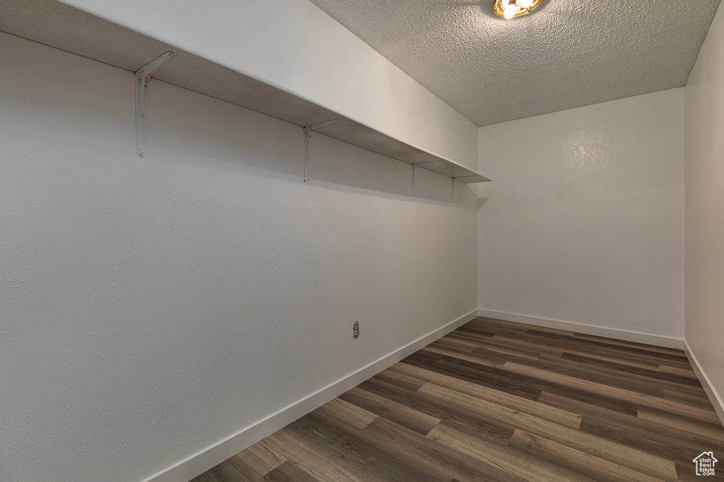 Walk in closet with dark wood-style floors