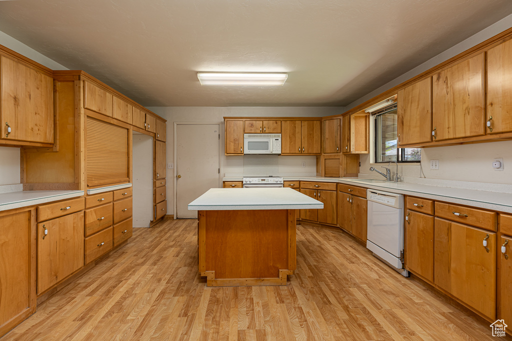 Kitchen with white appliances, light wood finished floors, light countertops, a center island, and brown cabinets