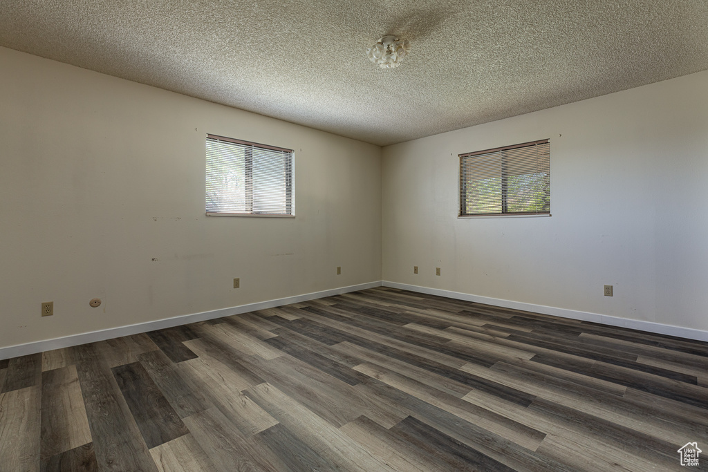 Unfurnished room with dark wood-style floors, a textured ceiling, and baseboards