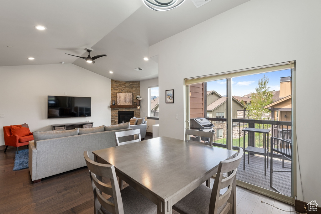 Dining space with a fireplace, wood finished floors, healthy amount of natural light, vaulted ceiling, and ceiling fan