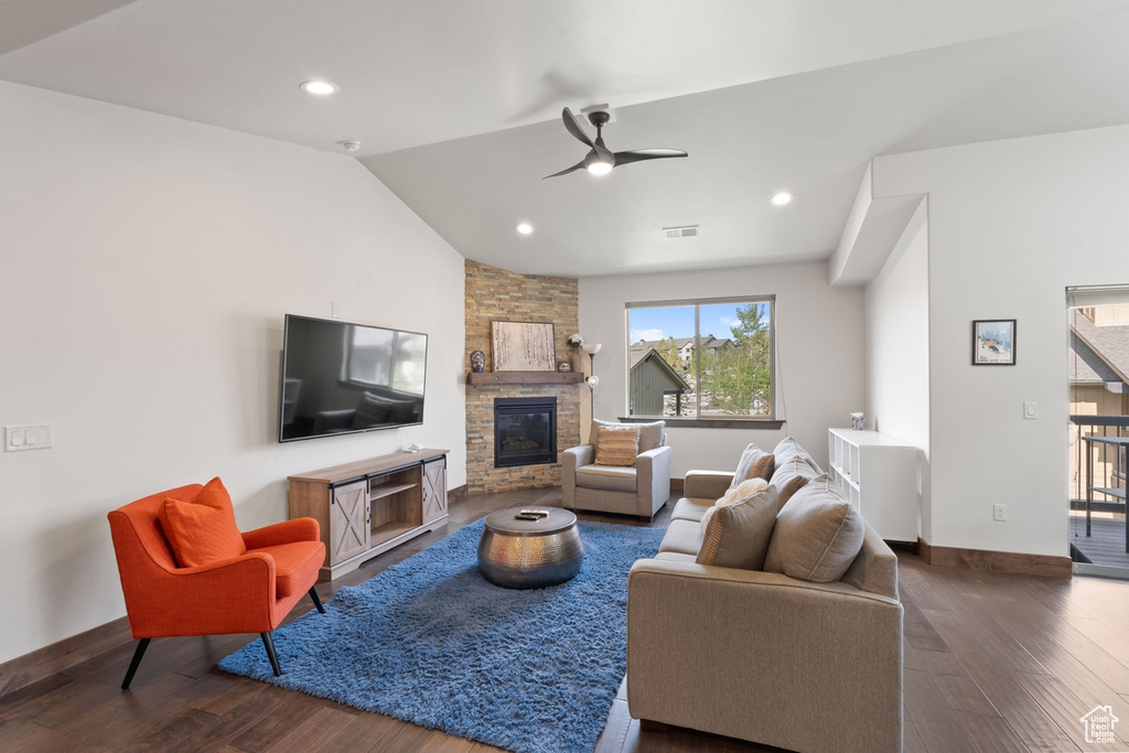 Living area with wood finished floors, a fireplace, a ceiling fan, vaulted ceiling, and baseboards