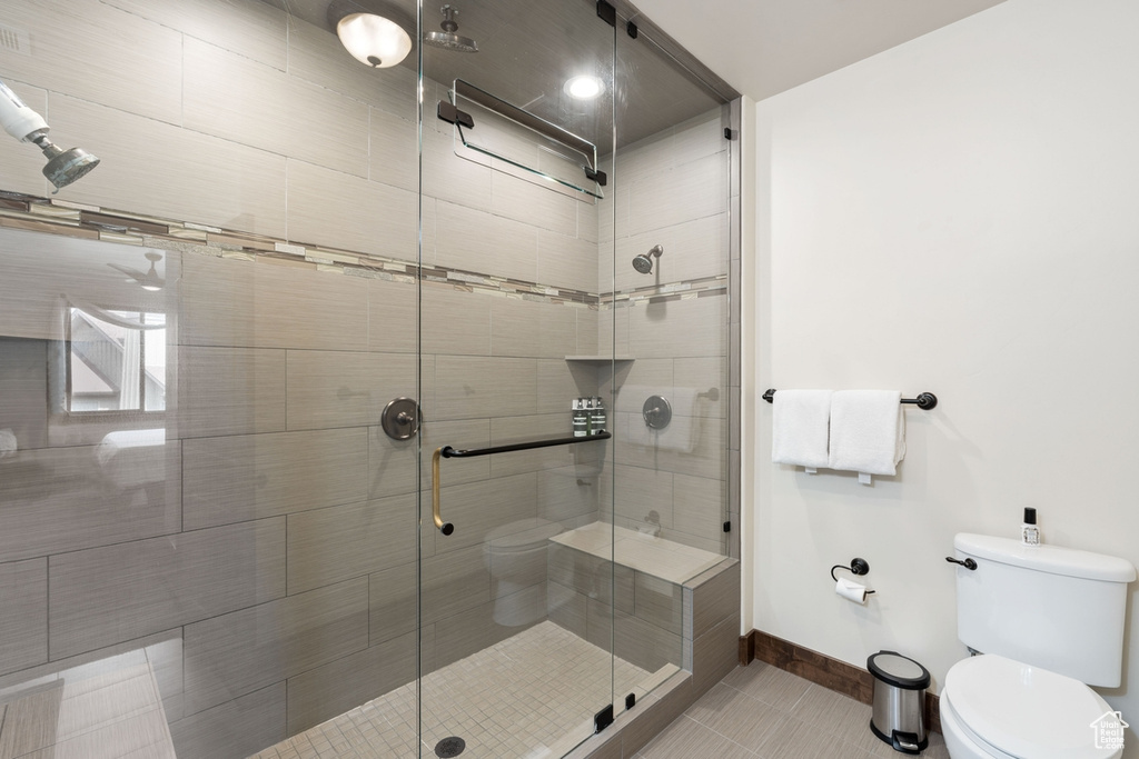 Full bathroom with toilet, tile patterned flooring, a stall shower, and baseboards
