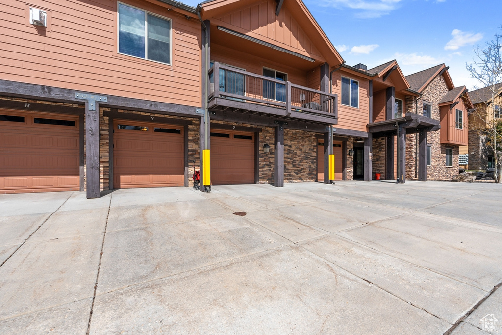 View of front of house with driveway, board and batten siding, a garage, and stone siding