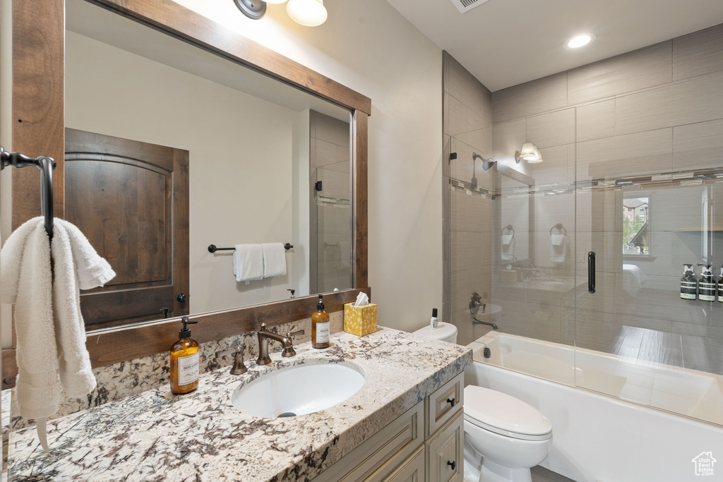 Bathroom with toilet, vanity, enclosed tub / shower combo, and recessed lighting