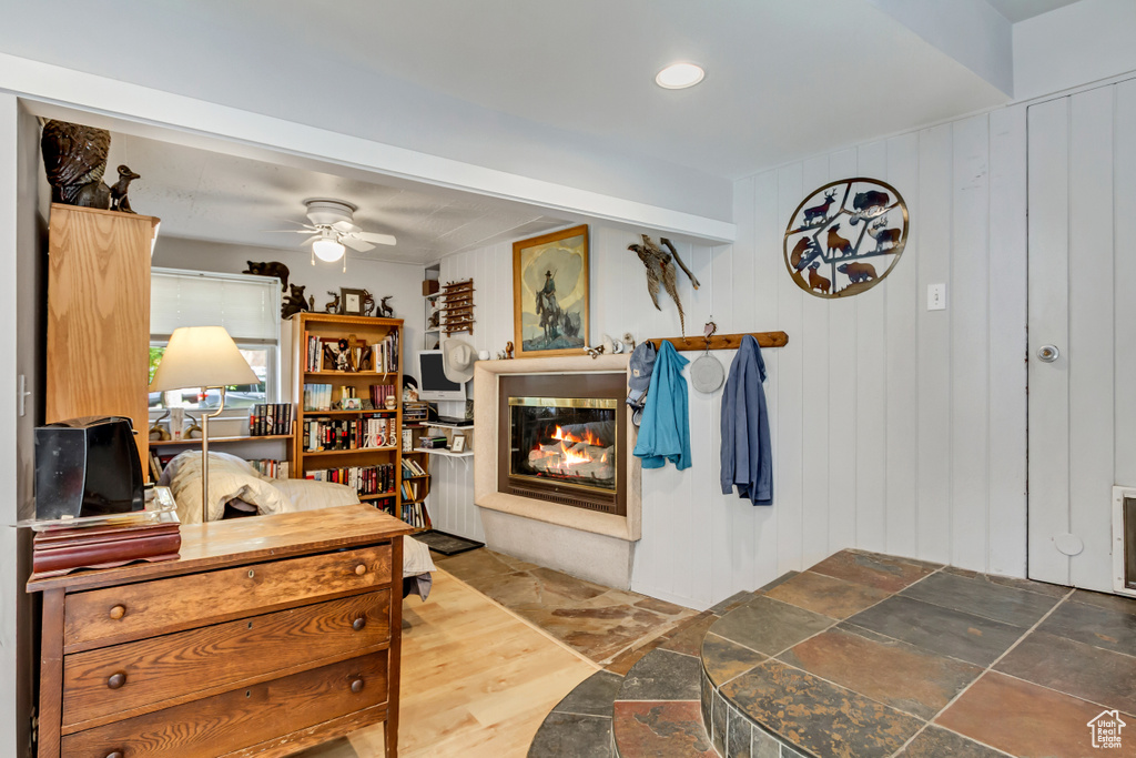 Interior space featuring a ceiling fan, a multi sided fireplace, and stone finish floors