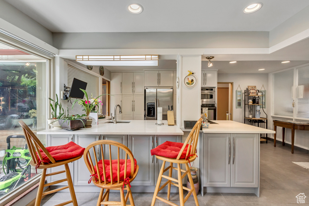 Kitchen featuring stainless steel appliances, a sink, a breakfast bar area, recessed lighting, and a peninsula