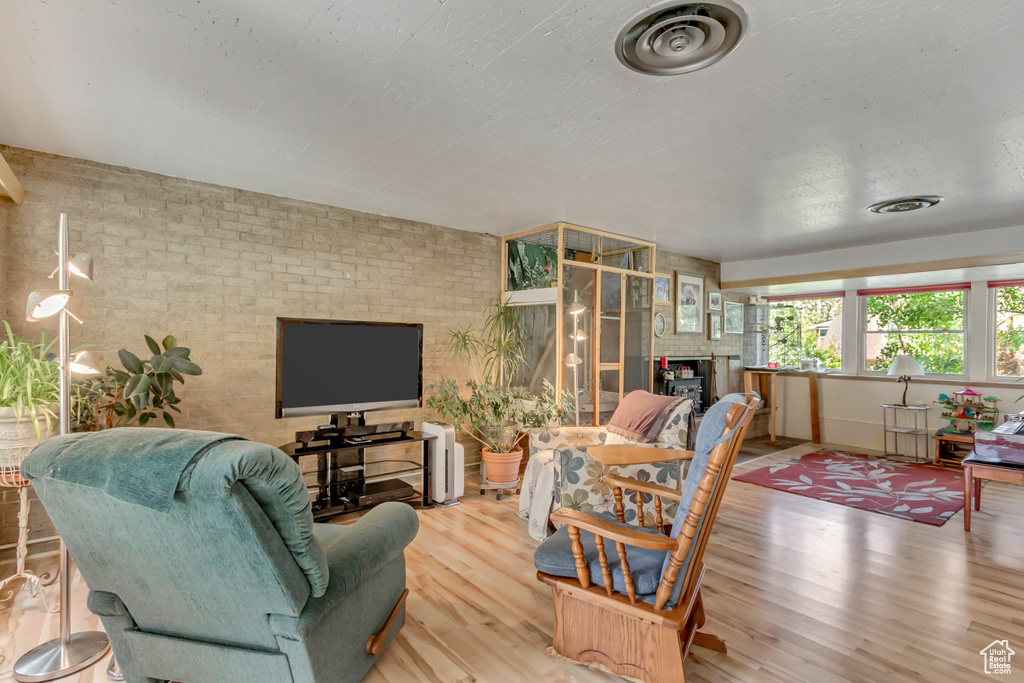 Living area featuring wood finished floors, brick wall, and a fireplace