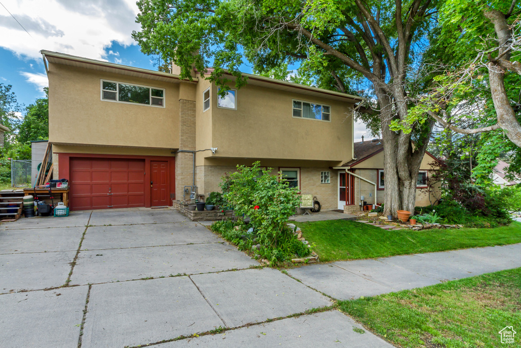 Multi unit property with stucco siding, a garage, a front lawn, and concrete driveway