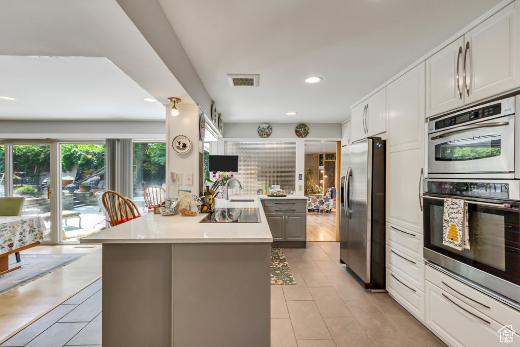 Kitchen with stainless steel appliances, light tile patterned floors, light countertops, a sink, and recessed lighting