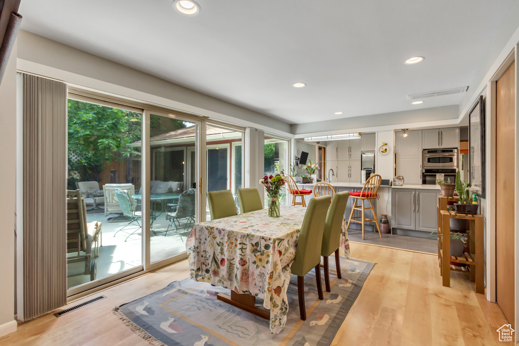 Dining room with light wood-style floors and recessed lighting