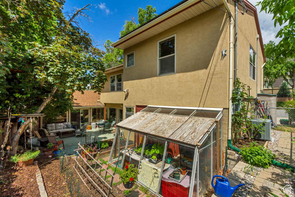 Back of property featuring an outdoor living space, stucco siding, a patio, a vegetable garden, and central air condition unit
