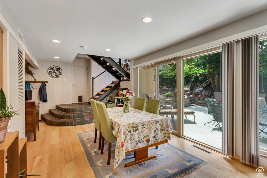 Dining room with stairs, light wood-style floors, recessed lighting, and wooden walls