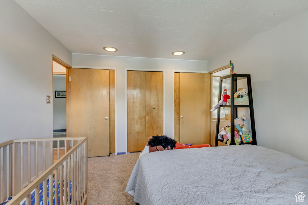 Bedroom featuring two closets, carpet flooring, and recessed lighting