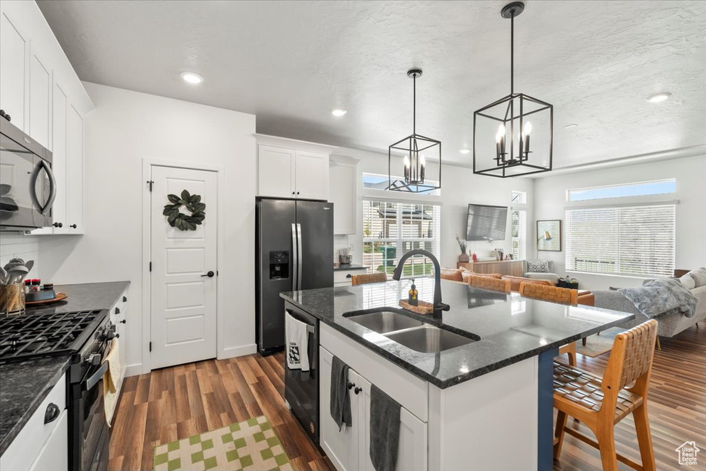 Kitchen featuring a sink, range with gas stovetop, stainless steel fridge, dark wood-style floors, and open floor plan