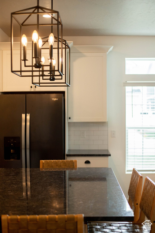 Kitchen featuring stainless steel fridge, healthy amount of natural light, backsplash, and white cabinetry