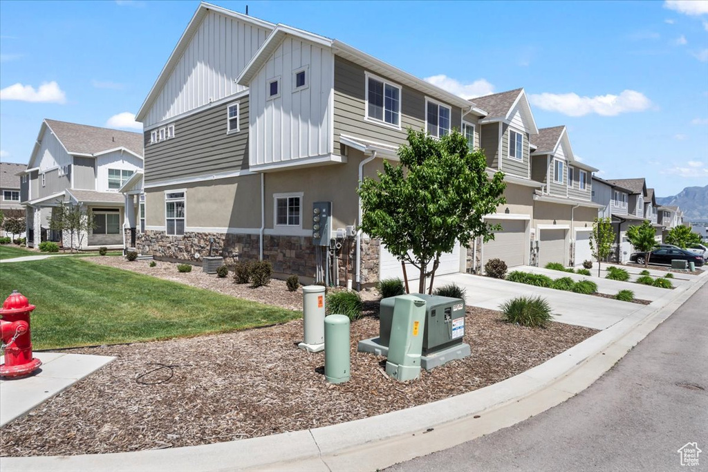 View of front of property featuring board and batten siding, stone siding, an attached garage, and a residential view