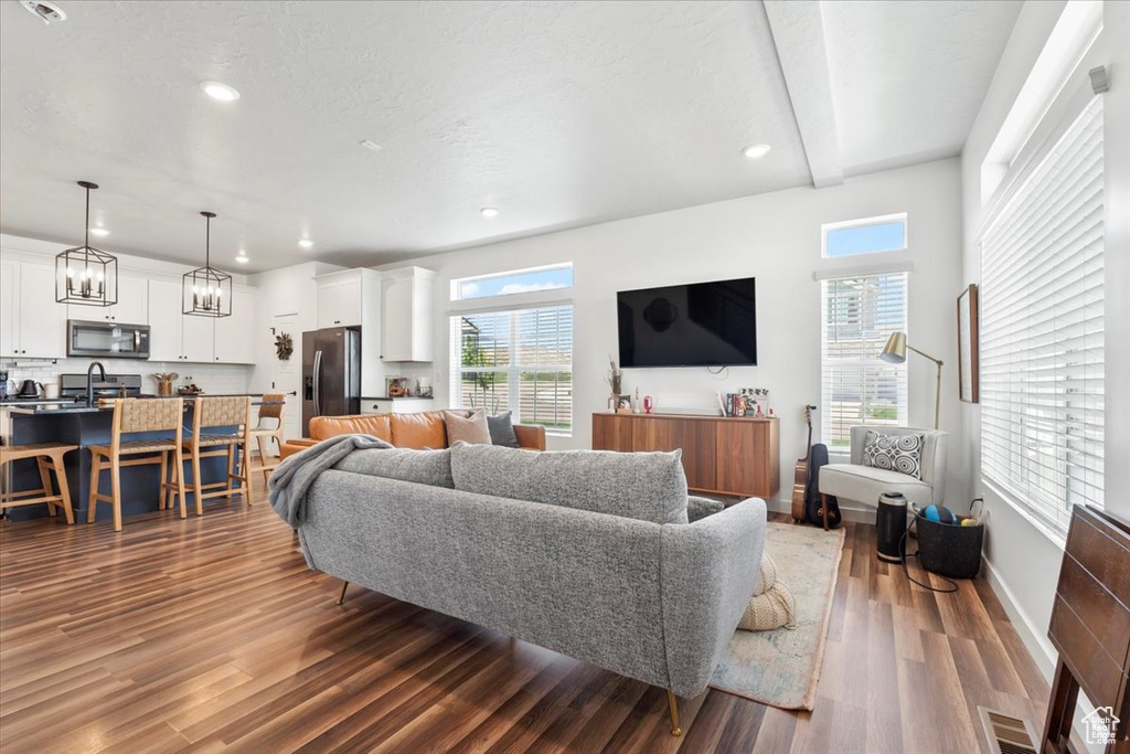 Living room featuring wood finished floors, healthy amount of natural light, recessed lighting, a chandelier, and baseboards