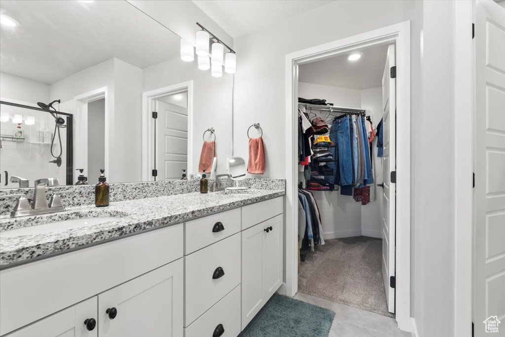 Full bathroom with a walk in closet, double vanity, tile patterned floors, and baseboards