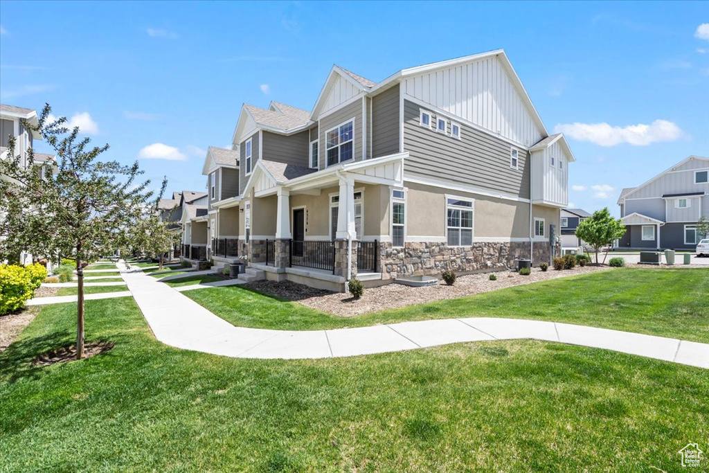 View of side of property with stone siding, a yard, a residential view, board and batten siding, and stucco siding