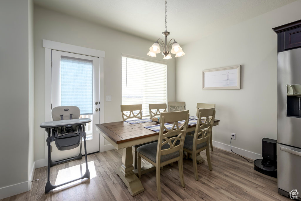 Dining area with a chandelier, light wood-style floors, and baseboards