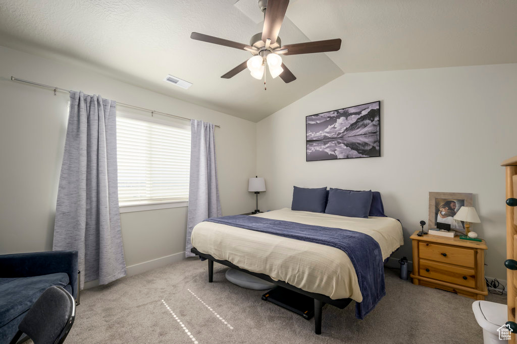 Carpeted bedroom with vaulted ceiling, a ceiling fan, and baseboards