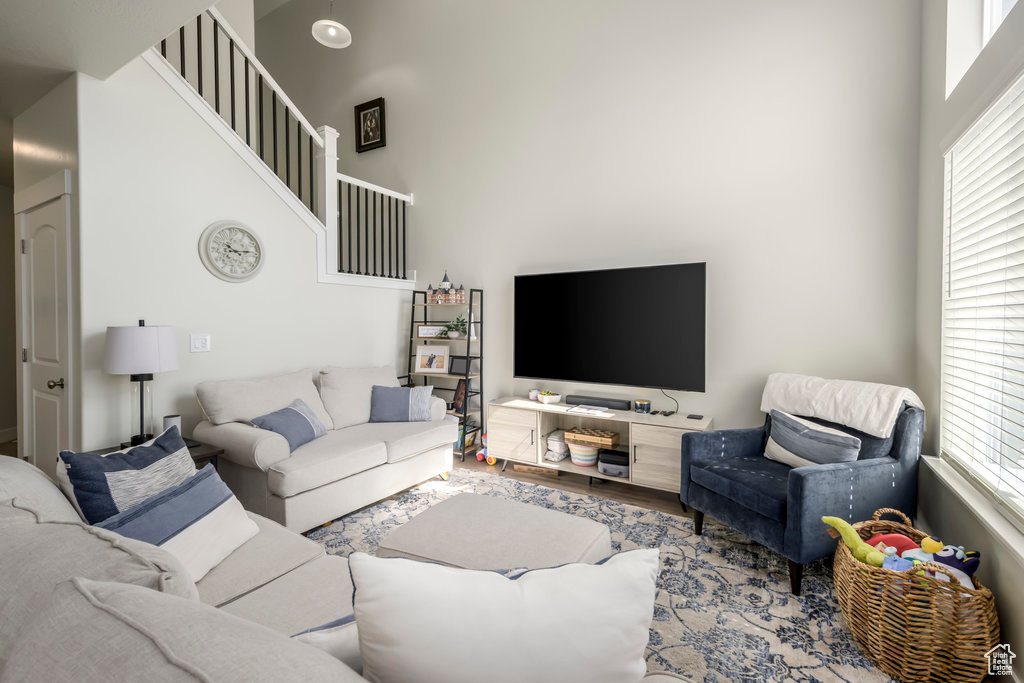 Living room with a towering ceiling, plenty of natural light, wood finished floors, and stairs