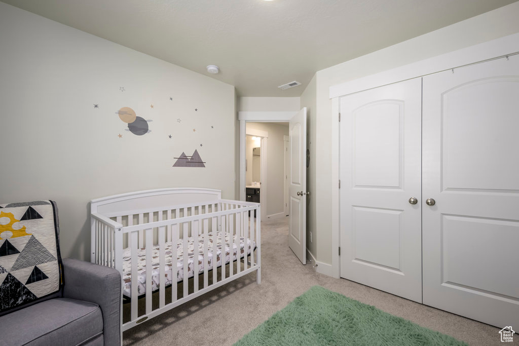 Bedroom with light carpet, a closet, baseboards, and a crib