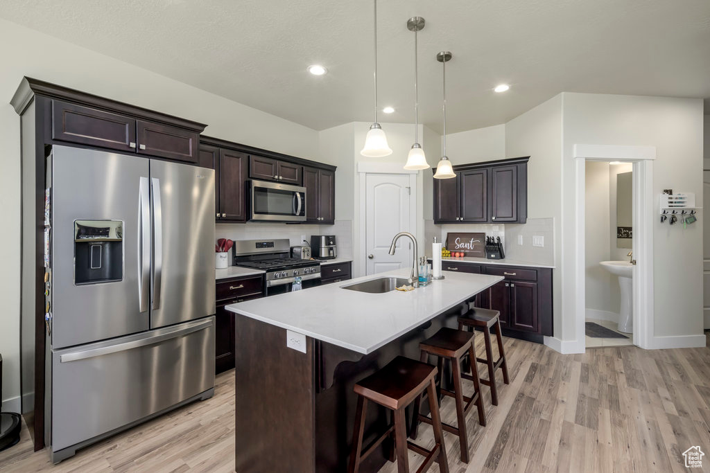 Kitchen featuring appliances with stainless steel finishes, a sink, light wood finished floors, light countertops, and recessed lighting