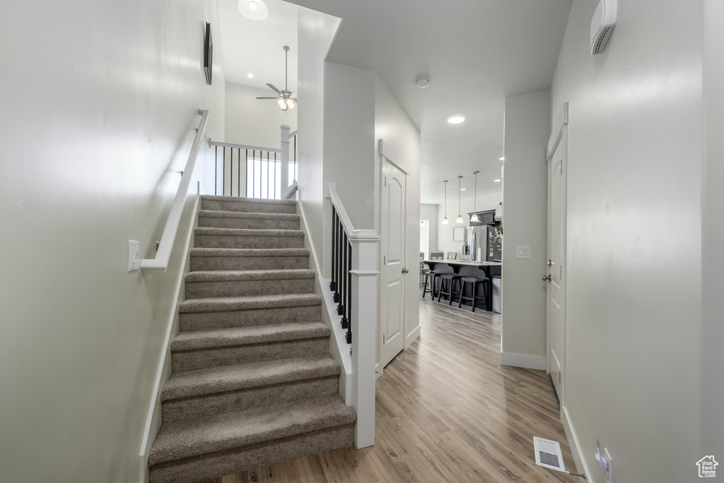 Staircase featuring a ceiling fan, wood finished floors, baseboards, and recessed lighting