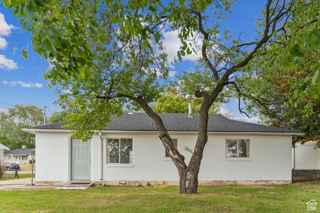 Back of property featuring a lawn and a shingled roof