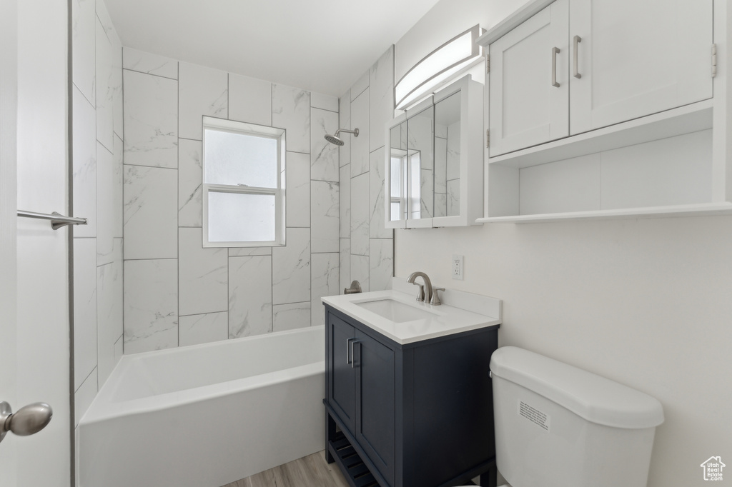 Full bathroom with vanity, toilet, washtub / shower combination, and wood finished floors