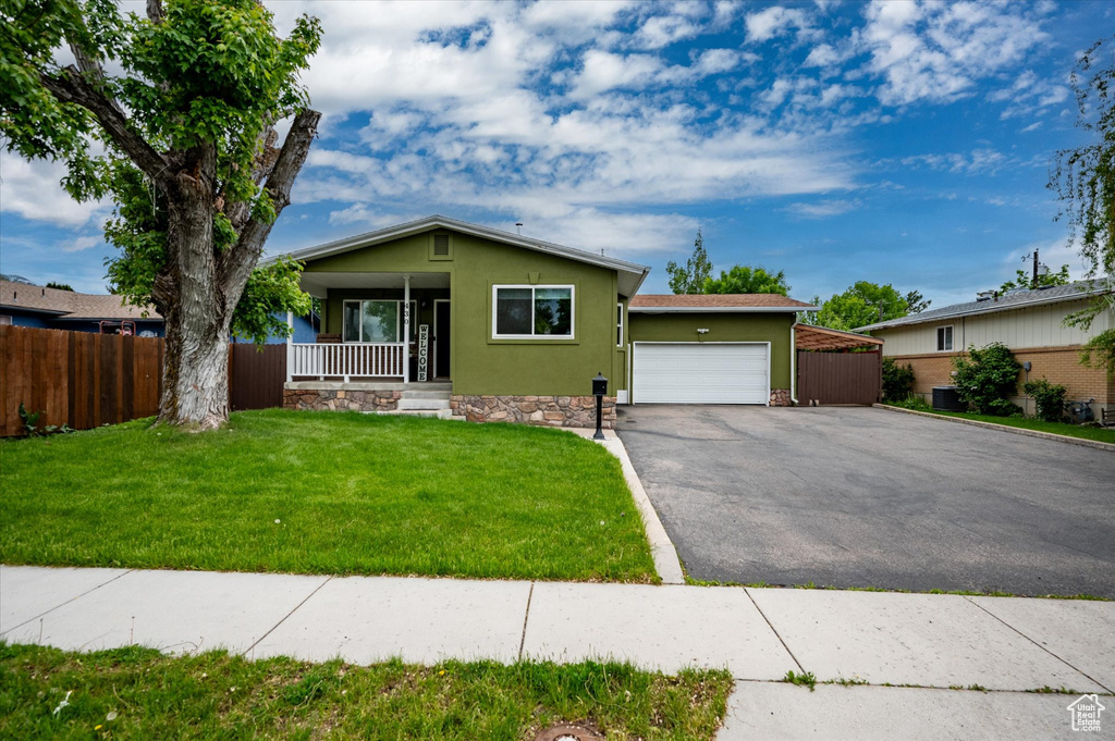 View of front facade featuring a garage, driveway, a porch, and stucco siding