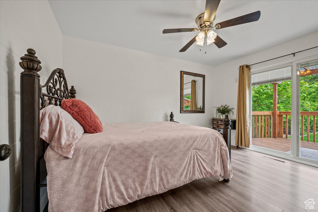Bedroom with access to outside, wood finished floors, multiple windows, and a ceiling fan