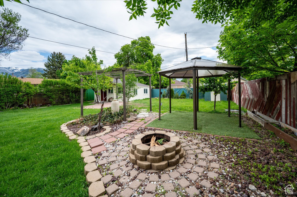 View of yard featuring an outdoor fire pit, a gazebo, a patio, and an outdoor structure