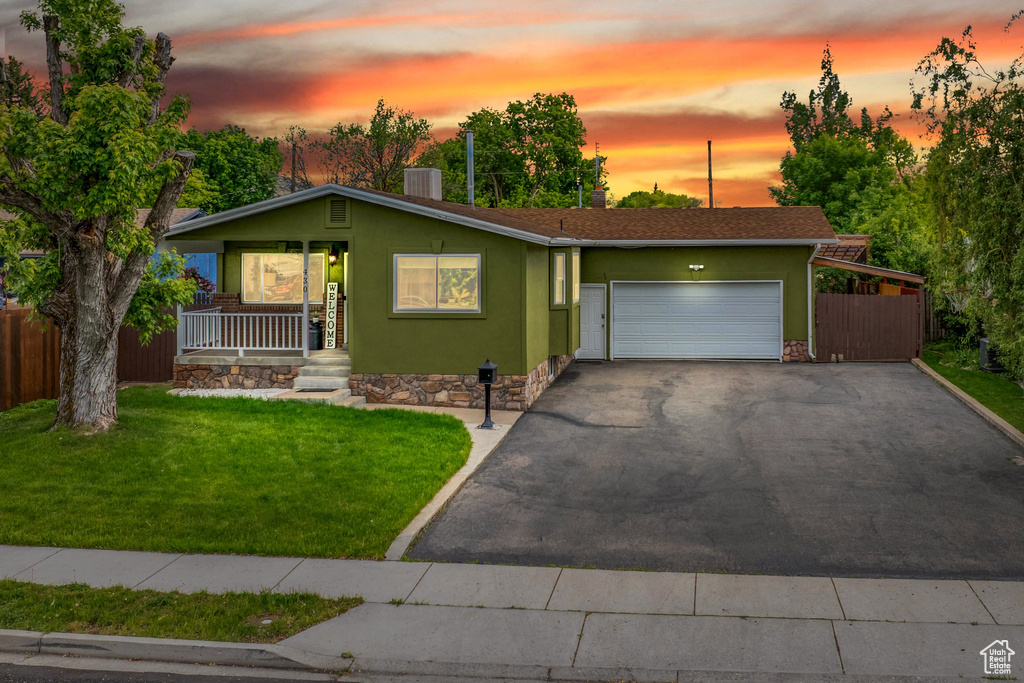 View of front of home featuring covered porch, an attached garage, asphalt driveway, stucco siding, and cooling unit