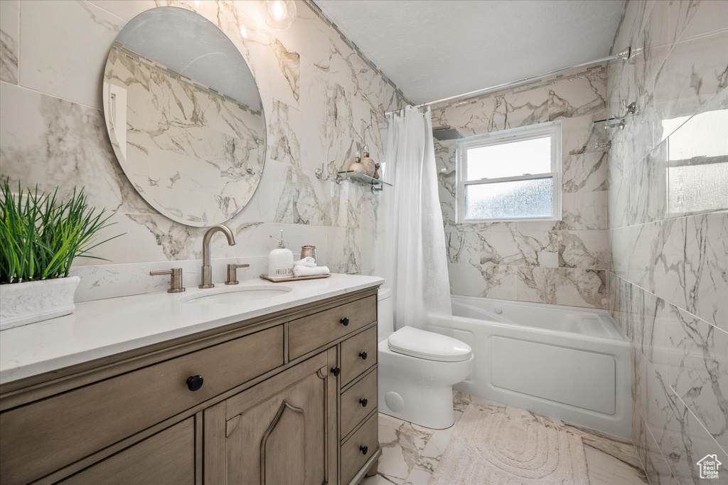 Bathroom featuring tile walls, shower / tub combo with curtain, vanity, toilet, and marble finish flooring