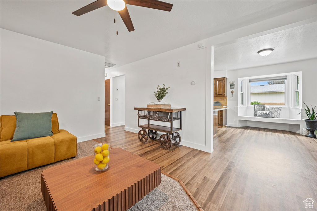 Living room with ceiling fan, wood finished floors, and baseboards
