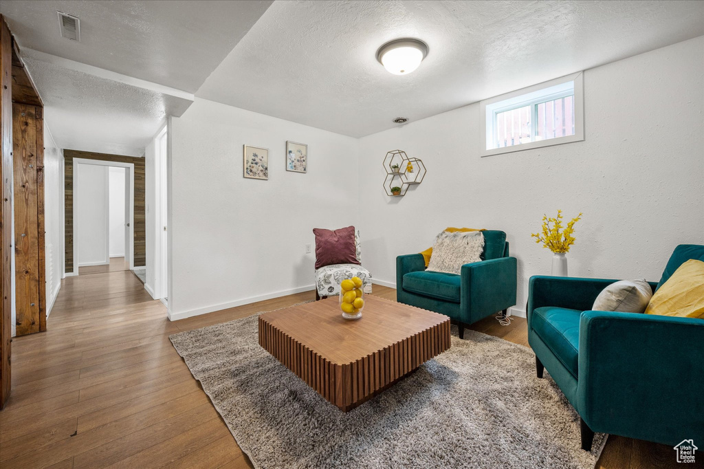 Living area featuring a textured ceiling, wood finished floors, and baseboards