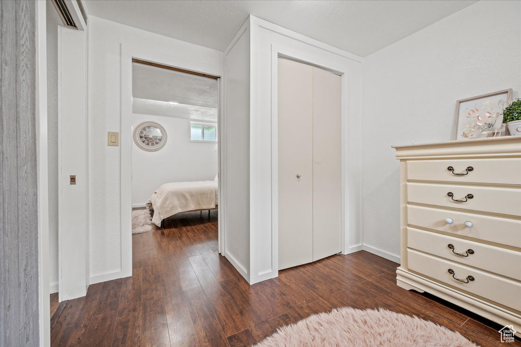 Bedroom with dark wood-type flooring, a closet, and baseboards