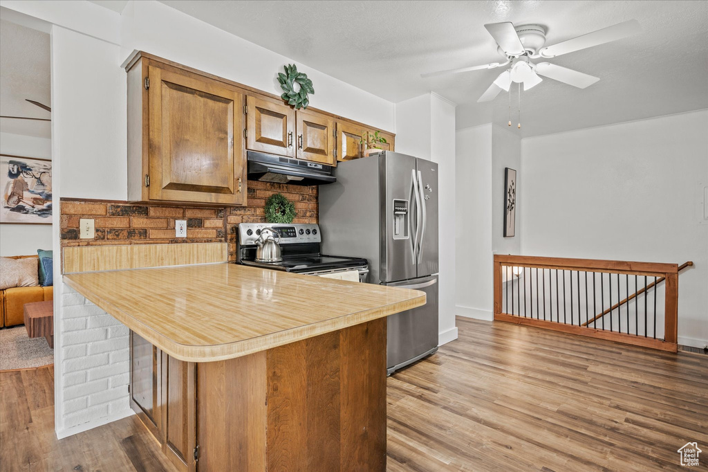 Kitchen featuring under cabinet range hood, appliances with stainless steel finishes, light wood-type flooring, light countertops, and ceiling fan