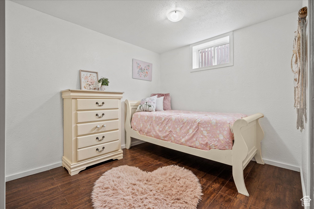 Bedroom with dark wood-style flooring and baseboards